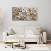 Quadro materico con foglie di ginkgo in rilievo bianco e oro appeso sopra divano chiaro, ambientazione soggiorno minimal.