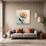 Soggiorno elegante con divano grigio e cuscini ocra; sulla parete un quadro su tela con fiore astratto verde acqua e arancione su sfondo chiaro.