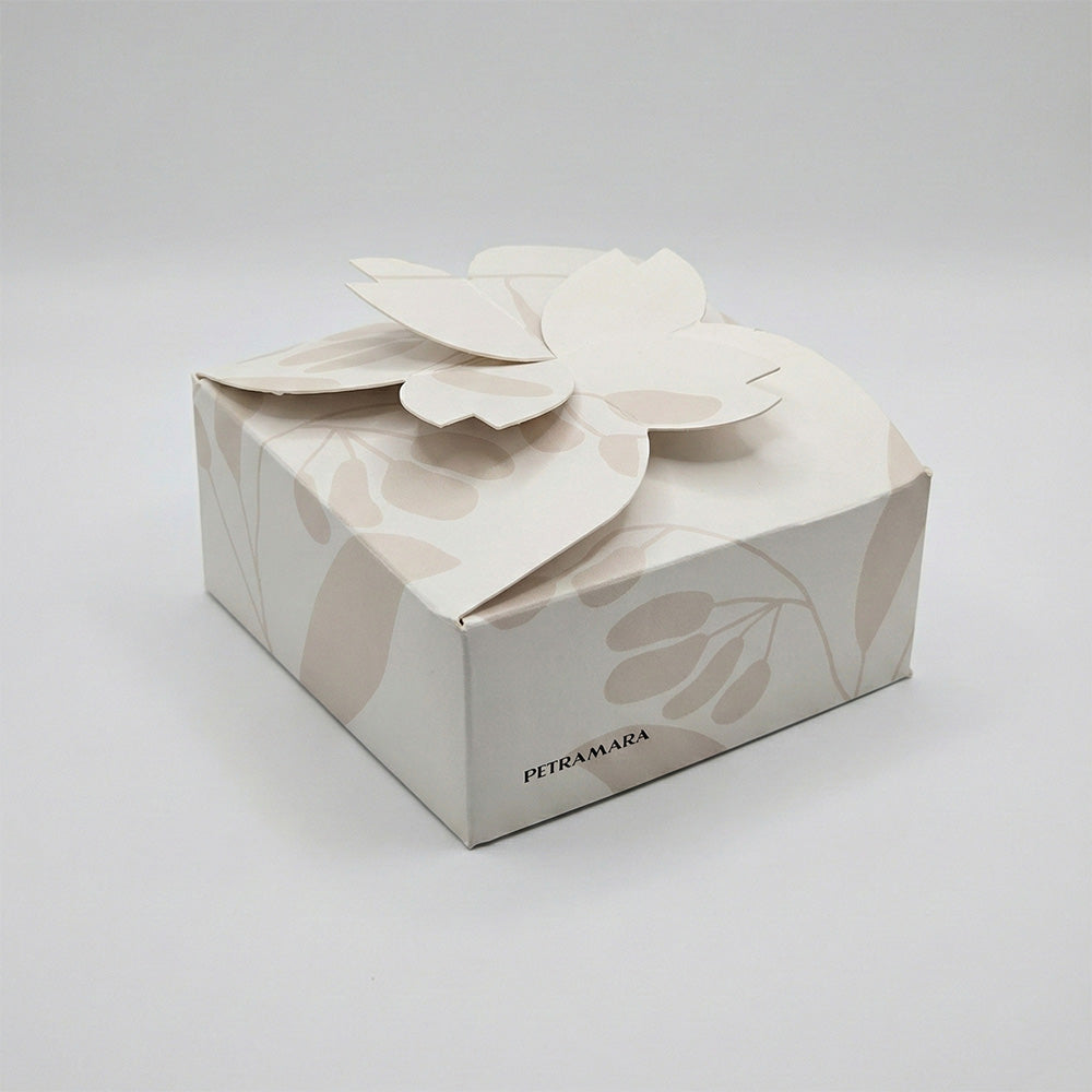 Scatola regalo Petramara color avorio con motivo botanico beige, chiusura a petali di fiore in rilievo, packaging elegante per profumatore ceramica