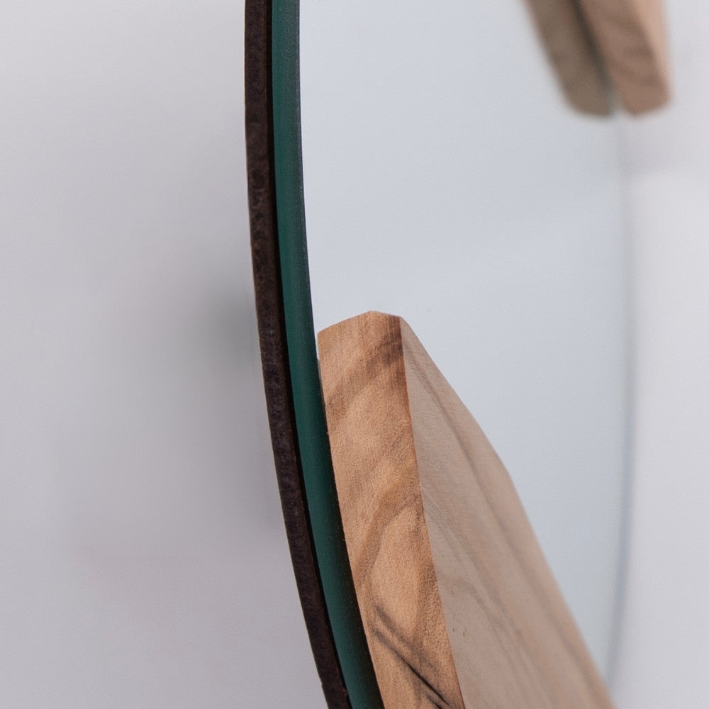 Dettaglio dello spessore dello specchio rotondo in ulivo, evidenziando la combinazione tra vetro spesso e cornice in legno.