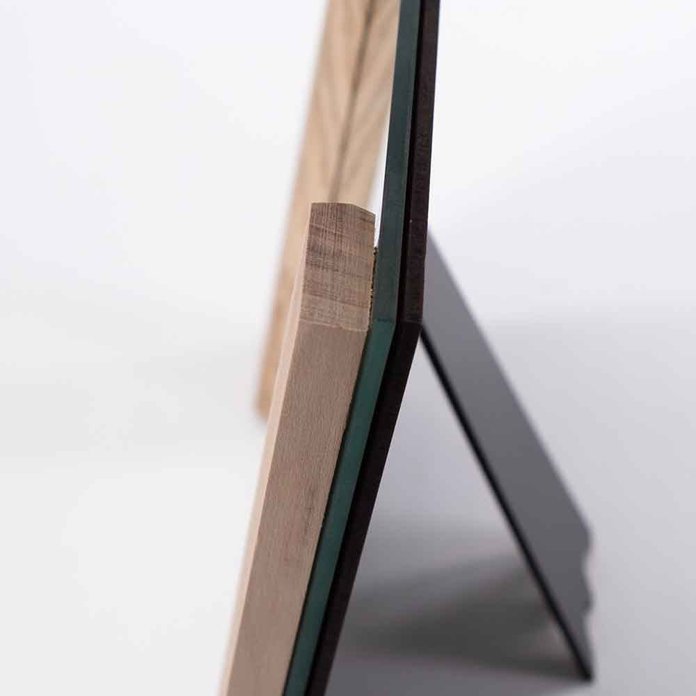 Dettaglio della cornice in legno d'ulivo con venature naturali accostata al vetro lucido, creando un contrasto elegante.