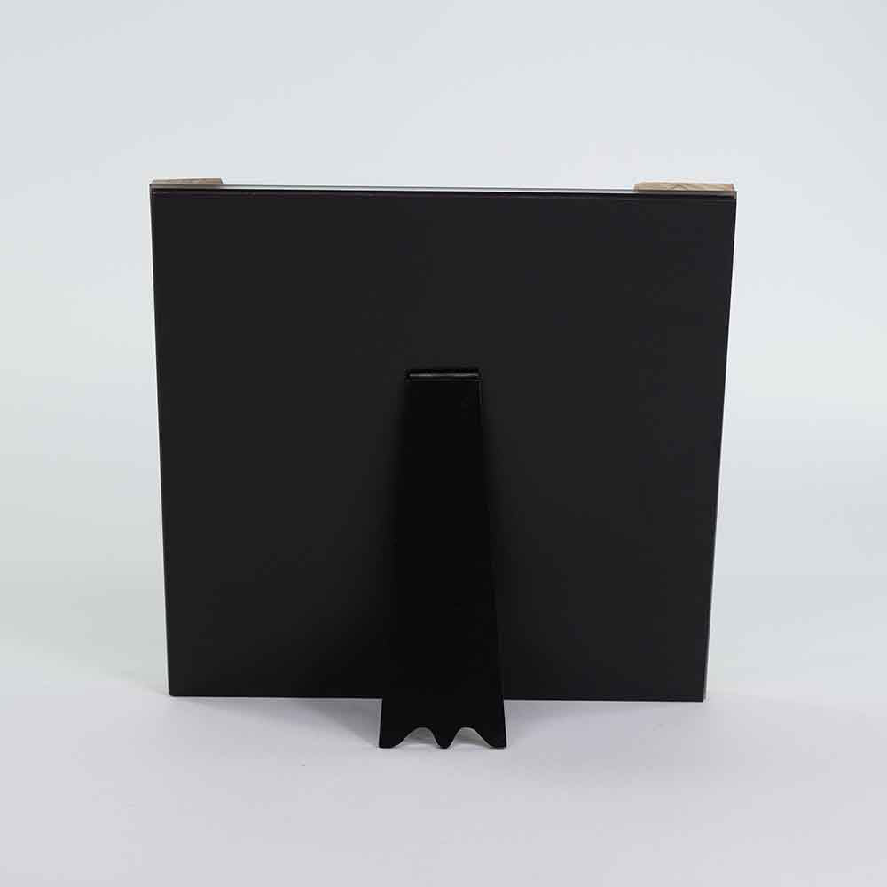 Retro dello specchio quadrato in ulivo, con superficie nera opaca e supporto centrale per un posizionamento stabile su tavolo.