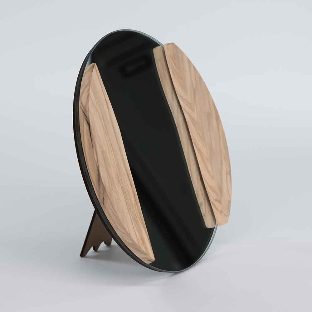 Vista laterale dello specchio rotondo in ulivo con cornice sagomata, mettendo in risalto la fusione tra legno e vetro.