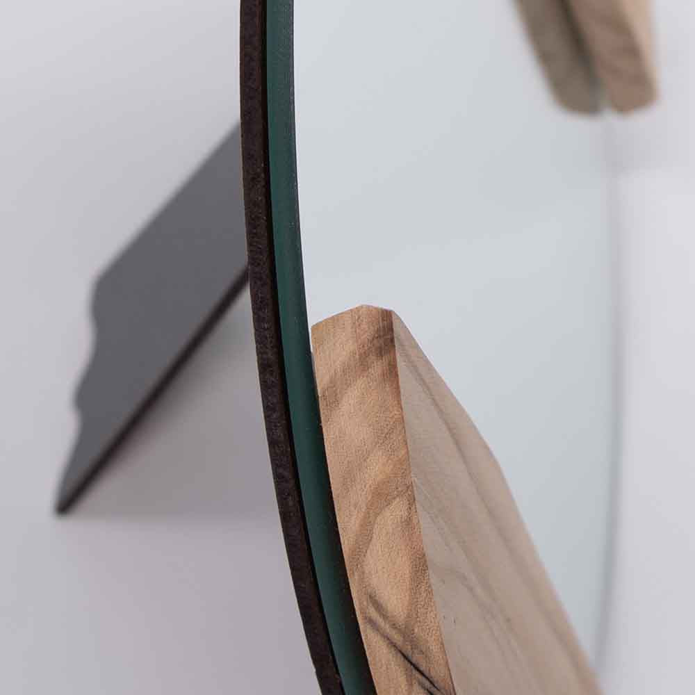 Dettaglio dello spessore dello specchio rotondo in ulivo, evidenziando la combinazione tra vetro spesso e cornice in legno.