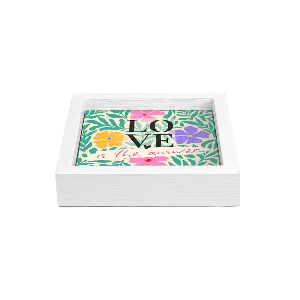 Svuotatasche bianco con scritta “LOVE is the answer” su sfondo floreale colorato con foglie verdi e fiori vivaci.