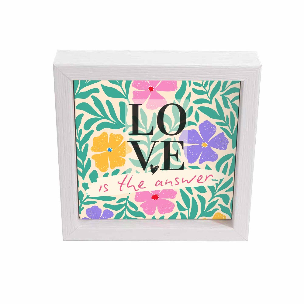 Svuotatasche bianco con frase “LOVE is the answer” su sfondo vegetale con fiori pastello e foglie verdi, frontale.