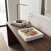 Svuotatasche in legno bianco con decoro geometrico giallo, verde e panna, con chiavi e portafoglio marrone su scrivania in legno scuro