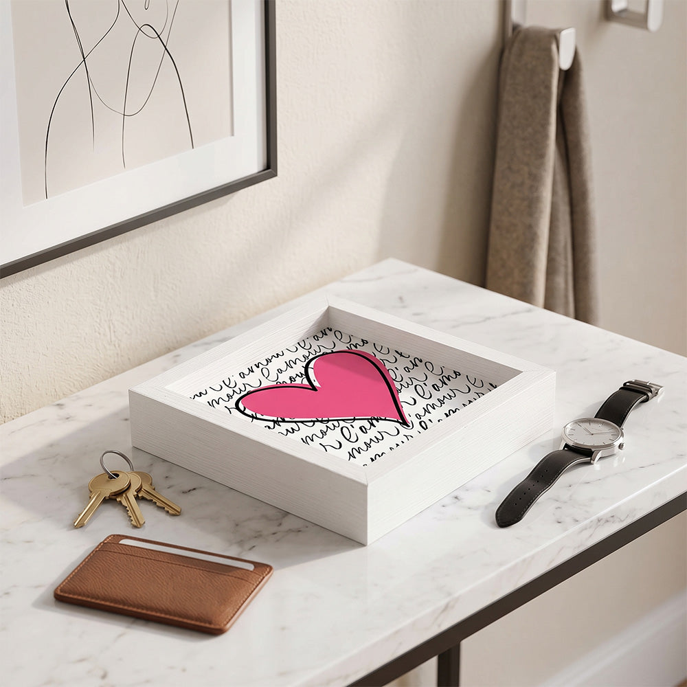 Svuotatasche in legno bianco con cuore rosa e scritta "l'amour" su fondo bianco, con chiavi dorate, portacarte e orologio su marmo