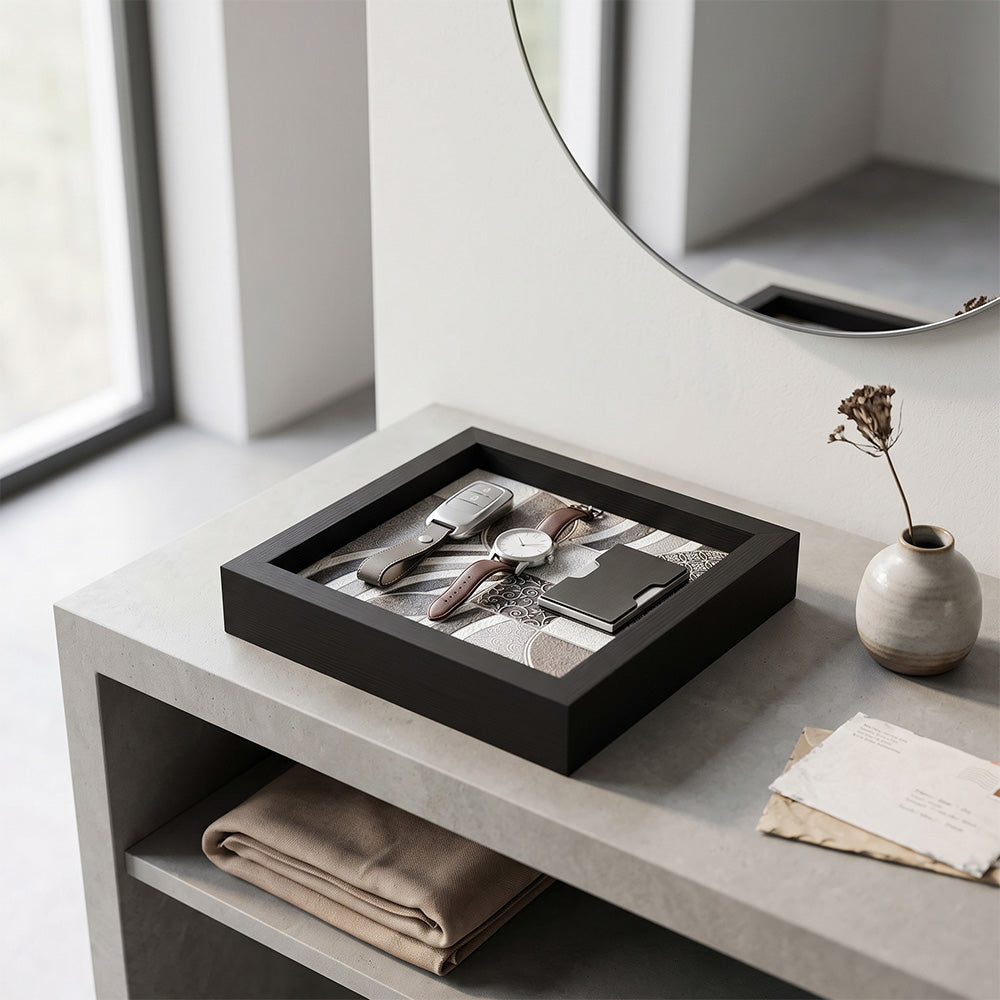 Svuotatasche in legno nero con decoro geometrico a righe grigio e beige, con portachiavi in pelle, orologio e portacarte su consolle in cemento