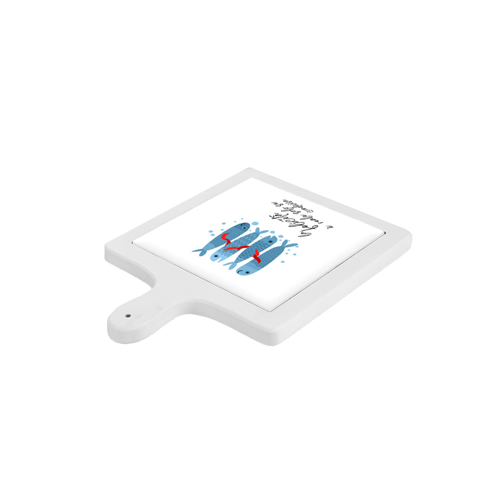 Tagliere in ceramica bianca visto lateralmente e disposto orizzontalmente, con decoro di pesci blu e scritta motivazionale.