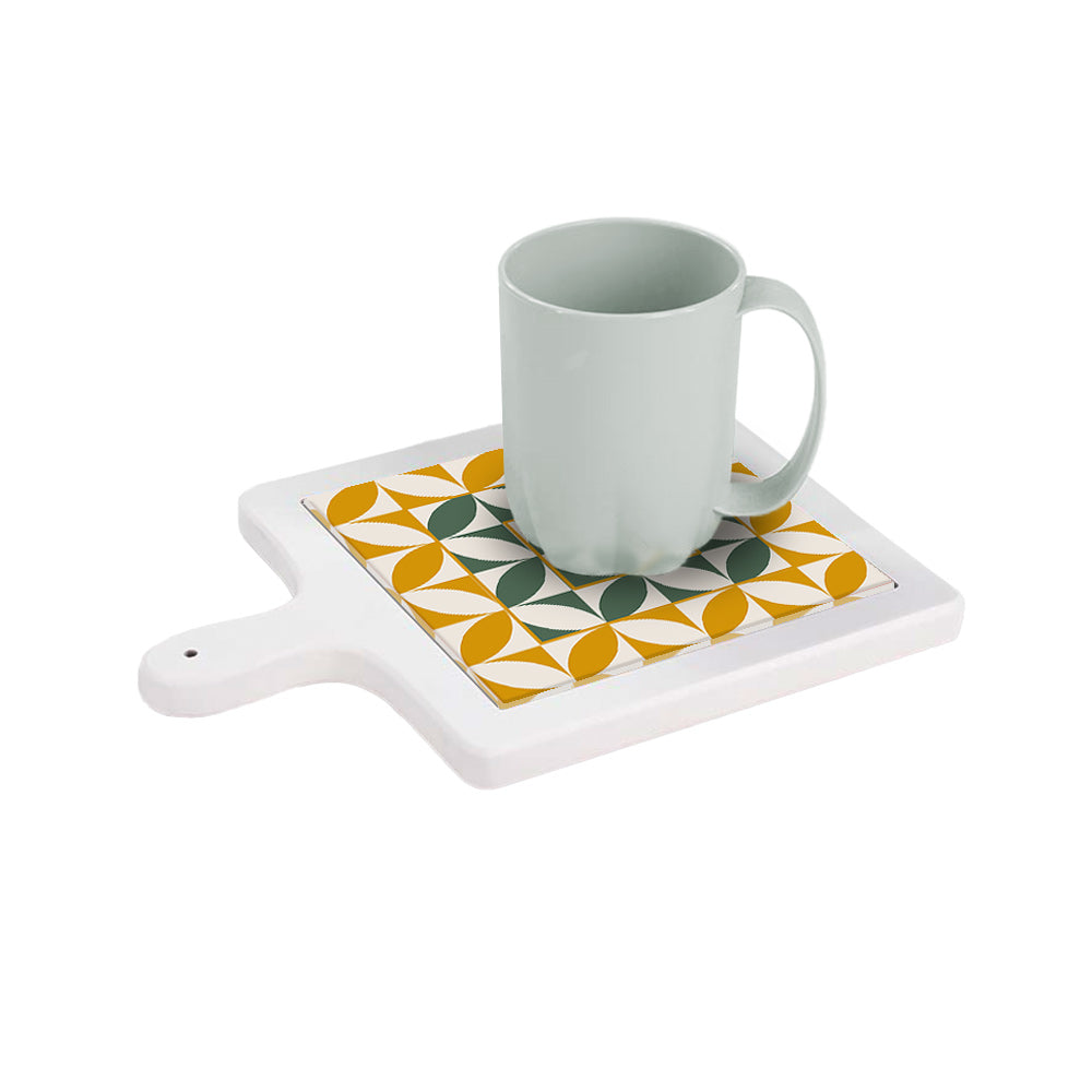 Tagliere in ceramica bianca orizzontale con tazza sopra, decorato con pattern a petali verdi e ocra su sfondo bianco.