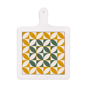 Tagliere verticale in ceramica bianca con decoro geometrico simmetrico in verde scuro e ocra su base bianca.