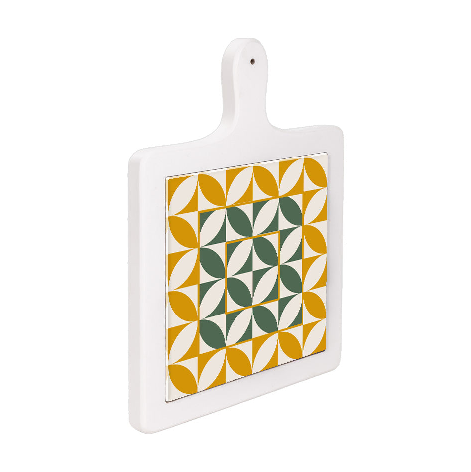 Tagliere verticale in ceramica bianca visto lateralmente, con decoro geometrico a petali verdi e ocra su fondo bianco.