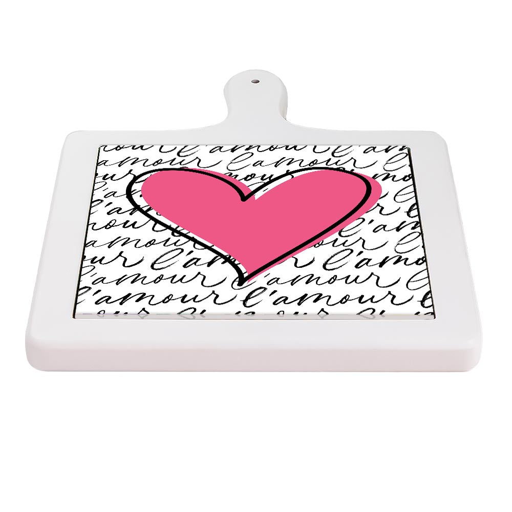 Tagliere orizzontale in ceramica bianca con grande cuore rosa al centro e sfondo con scritta continua “l’amour” in corsivo nero.