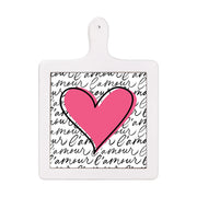 Tagliere verticale in ceramica bianca con cuore rosa acceso e sfondo con scritta “l’amour” nera ripetuta in corsivo su bianco