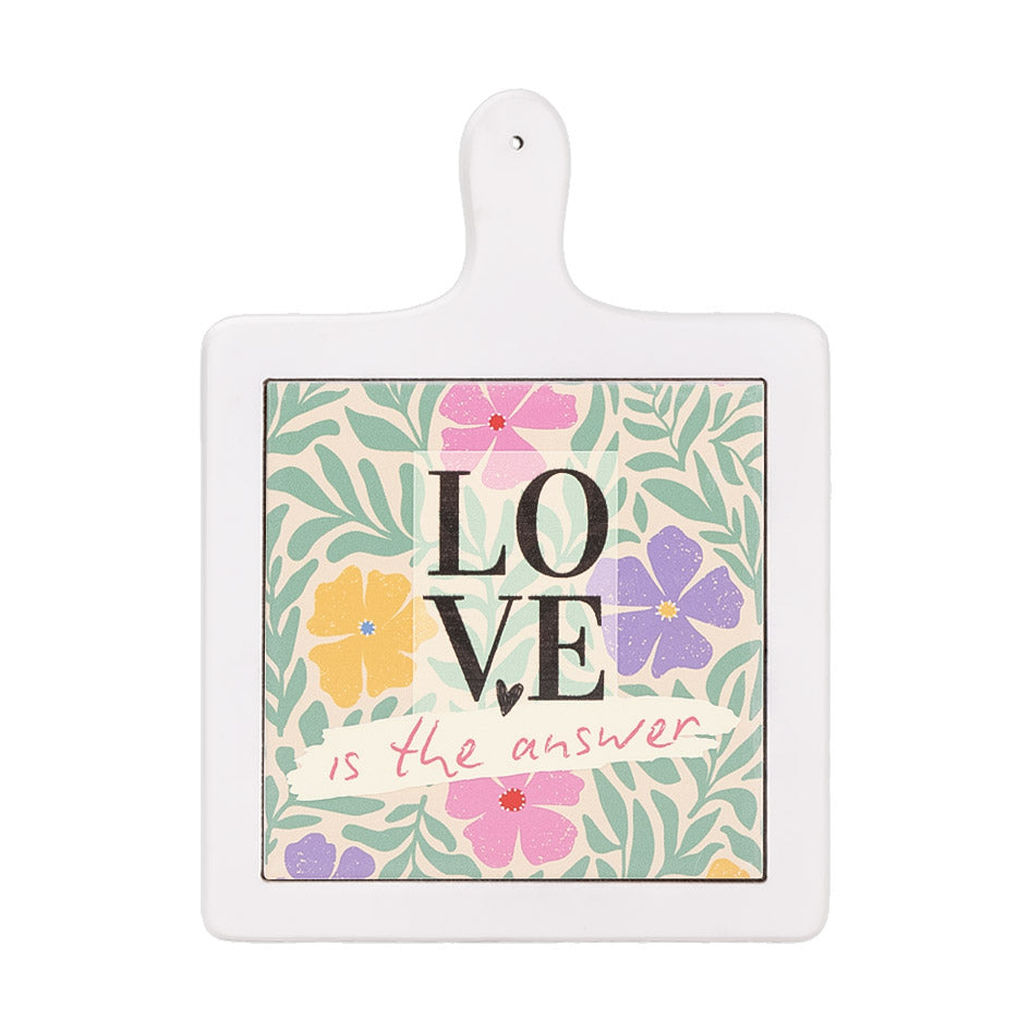 Tagliere verticale in ceramica bianca con fiori colorati e scritta decorativa “Love is the answer” al centro su fondo chiaro.