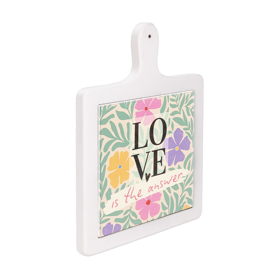 Tagliere in ceramica bianca verticale visto lateralmente, decorato con fiori vivaci e frase centrale “Love is the answer”.