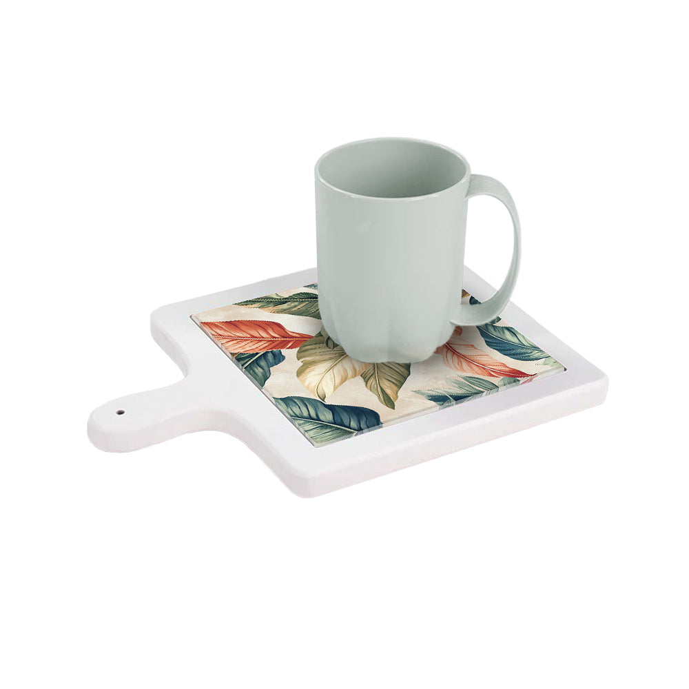 Tagliere in ceramica bianca orizzontale con tazza appoggiata, decorato con foglie esotiche dai toni caldi e naturali.