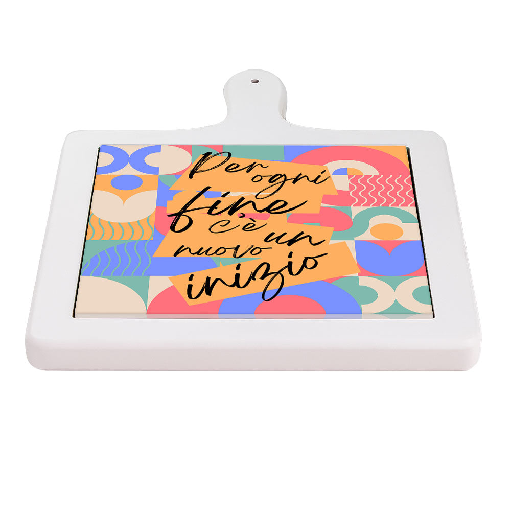 Tagliere con ceramica vista orizzontale con pattern astratto e scritta motivazionale nera su sfondo di forme geometriche colorate.