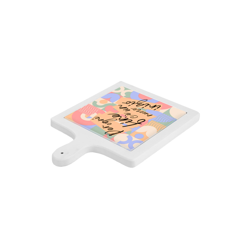 Tagliere visto in orizzontale da lato basso, con base bianca e decoro grafico multicolore con frase ispirazionale.