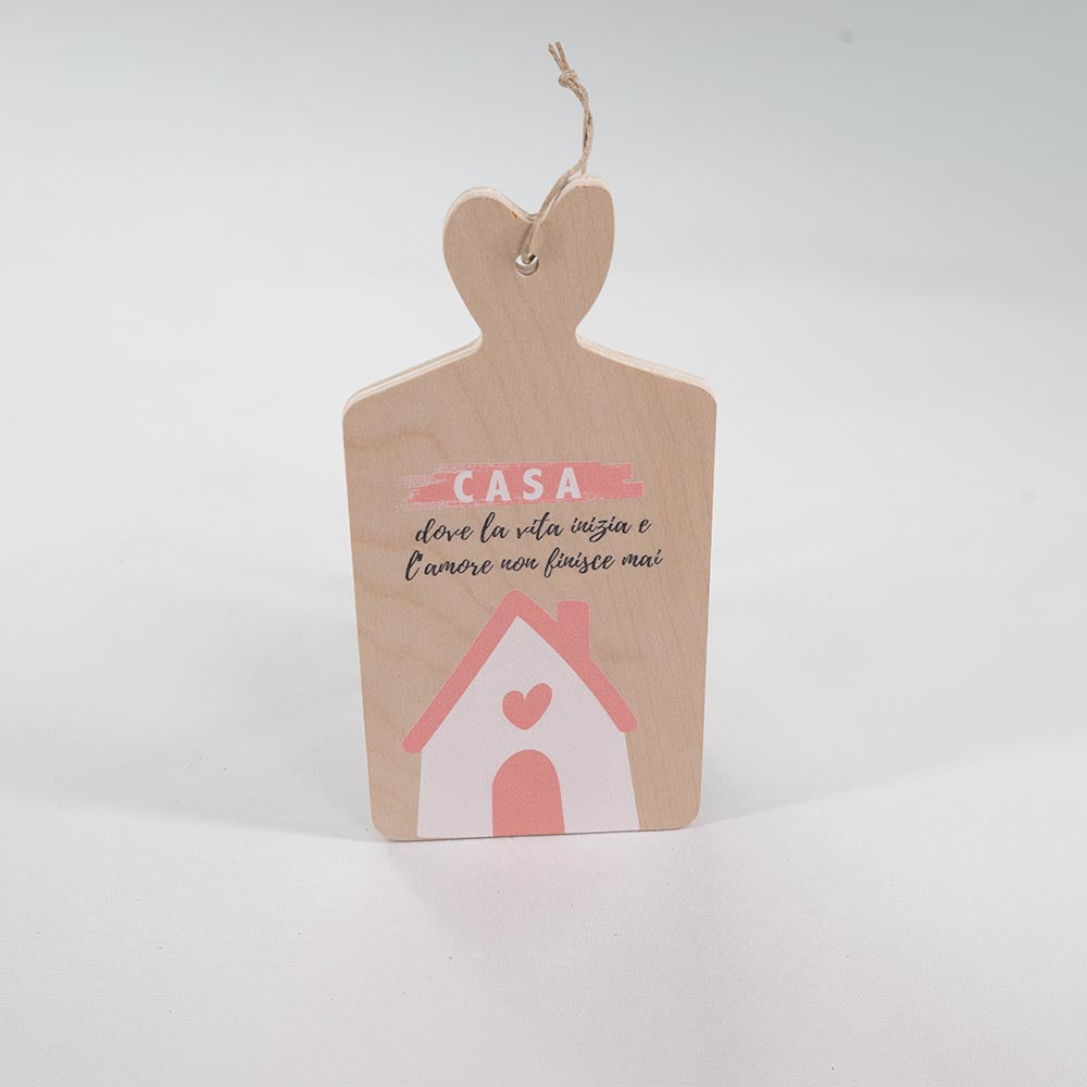Tagliere decorativo in legno con scritta “Casa” e casetta rosa, in verticale su sfondo neutro, manico sagomato a cuore con cordino.