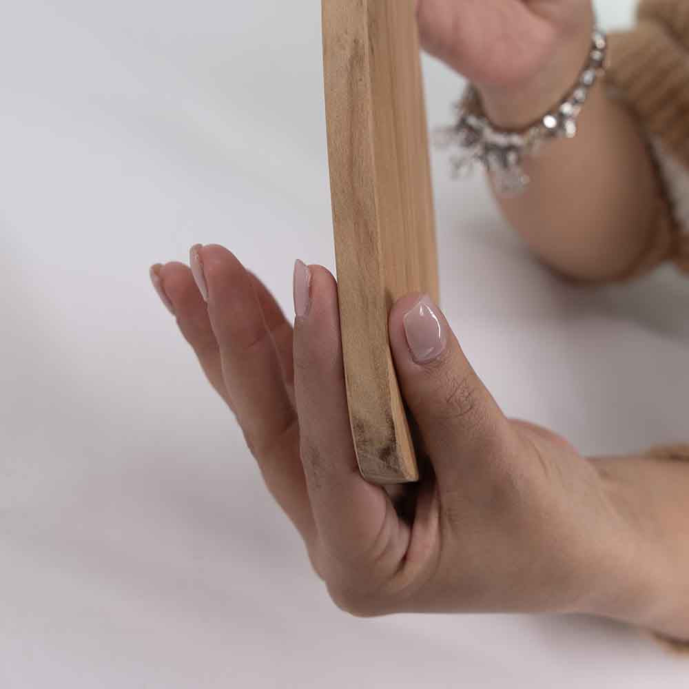 Primo piano sullo spessore di un tagliere in ulivo bombato, mostrando la solidità e la finitura liscia del legno naturale.