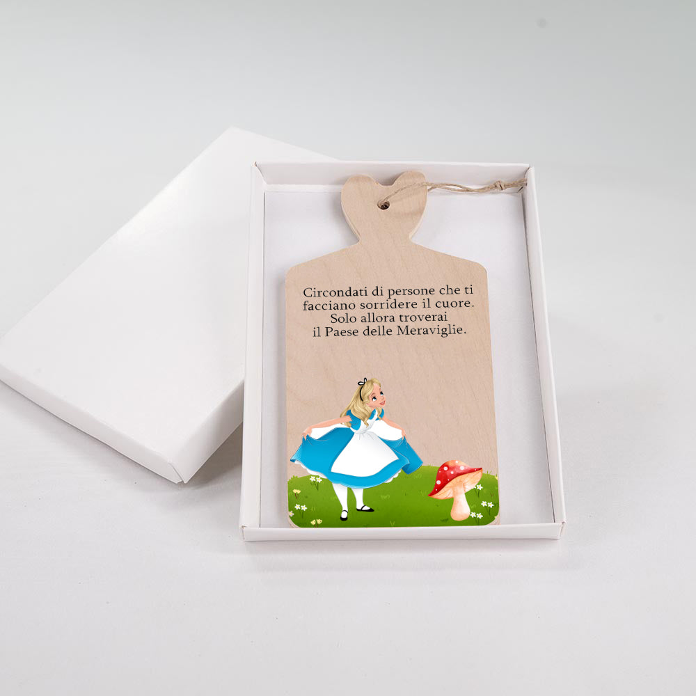 Tagliere in legno con illustrazione di Alice nel Paese delle Meraviglie su prato verde con fungo rosso e frase sul sorrire del cuore.
