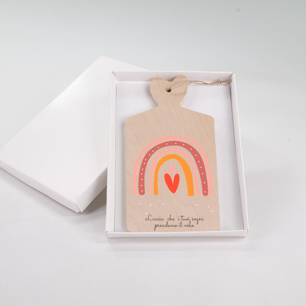 Tagliere in legno con arcobaleno in rosa, bordeaux e arancione con cuore rosso e scritta motivazionale sui sogni, presentato in scatola bianca.