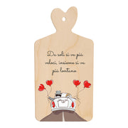 Tagliere in legno a forma di cuore con frase “Da soli si va più veloci, insieme si va più lontano” e illustrazione di sposi in auto con palloncini rossi a cuore.