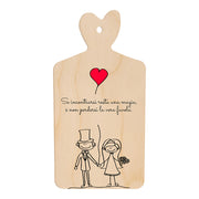 Tagliere in legno a forma di cuore con frase romantica e illustrazione stilizzata di sposi che si tengono per mano sotto un palloncino rosso a forma di cuore.