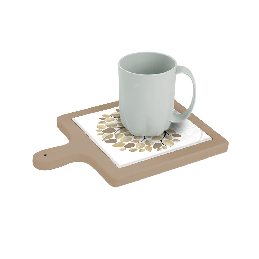 Tagliere quadrato beige con decoro ad albero con foglie nei toni neutri, visto inclinato con tazza appoggiata sopra.
