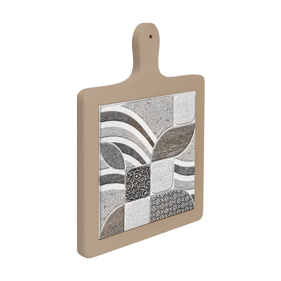 Tagliere in ceramica con manico beige visto di lato, decoro a mosaico geometrico con foglie e archi in toni grigio e bianco.