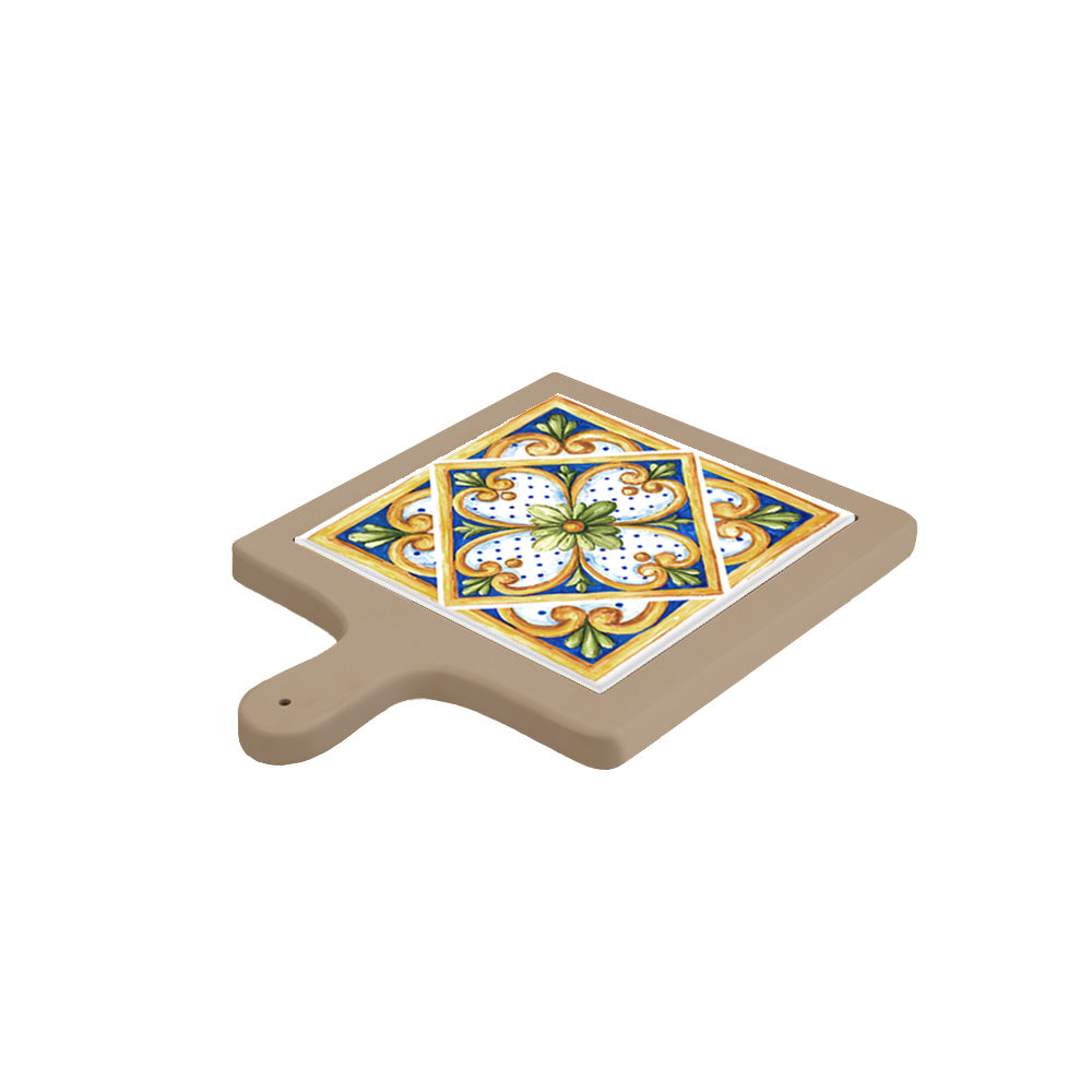 Tagliere in ceramica beige in appoggio inclinato, decorato con piastrella centrale floreale dai toni giallo oro, verde e blu acceso.