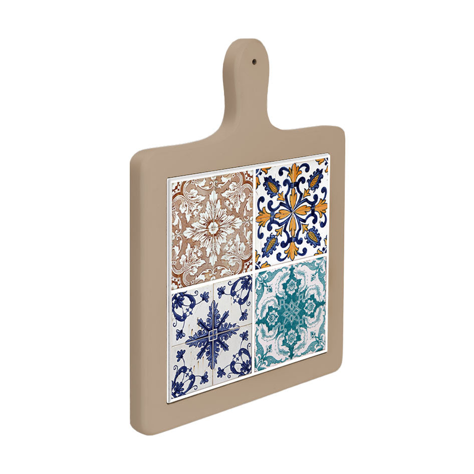 Tagliere in ceramica beige visto lateralmente, con decoro a quattro piastrelle maiolica in stile classico dai toni accesi e motivi floreali.